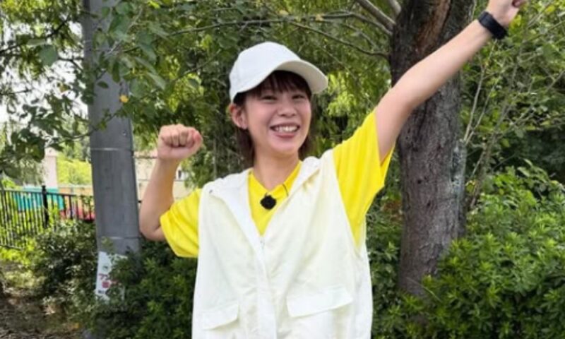 屋外でキャップとベスト姿の髙木菜那さんが笑顔でポーズをとるオフショット、ベスコングルメ出演時の様子