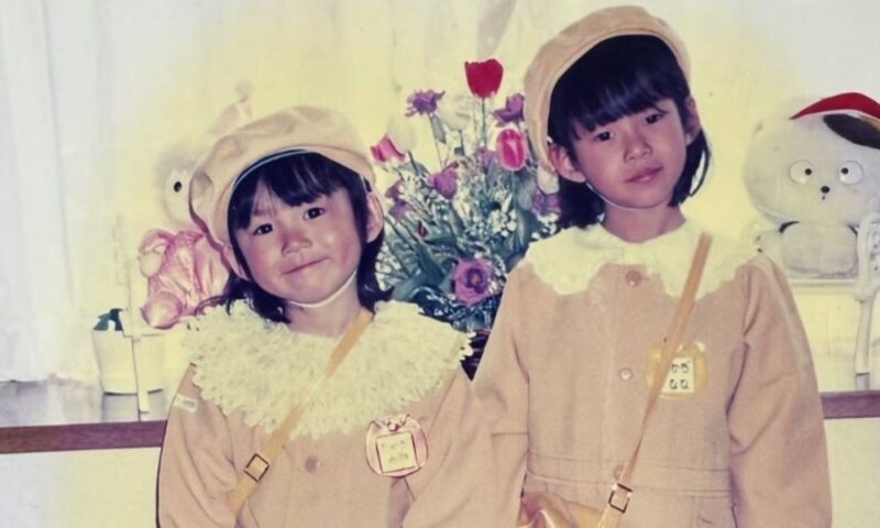幼少期の髙木菜那さんと妹・髙木美帆さんが並んで写る写真、帽子と園児服姿で微笑むツーショット