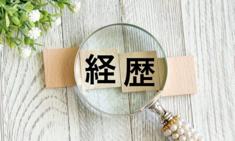木製ブロックに書かれた経歴の文字と虫眼鏡