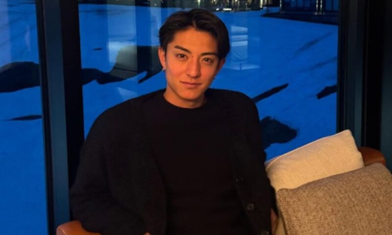 田中宏武が雪景色の窓辺のソファに座り微笑む黒カーディガン姿の写真