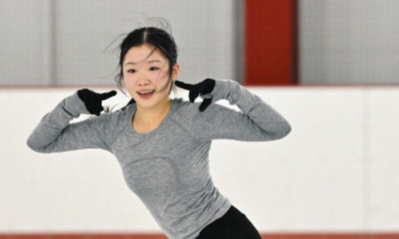 グレーのウェア姿でリンク上に立ち、笑顔でポーズをとる中井亜美さん