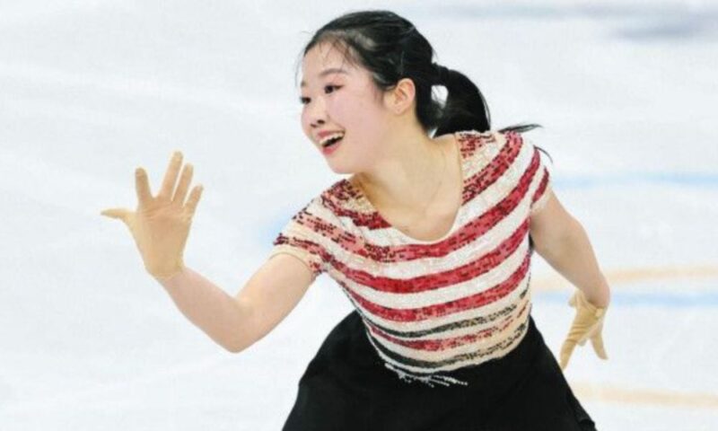 赤と白の衣装でリンク上を滑り、手を伸ばす中井亜美さん