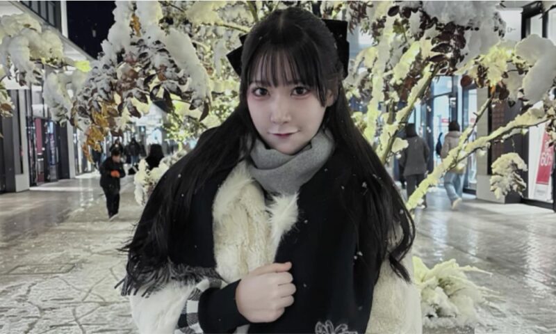 雪景色の屋外会場で、コートとマフラーを着用した愛成来来が写るイベント時の写真