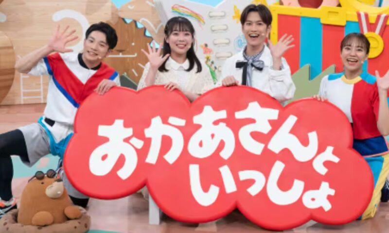 『おかあさんといっしょ』出演者が番組ロゴボードを持って手を振る集合ショット