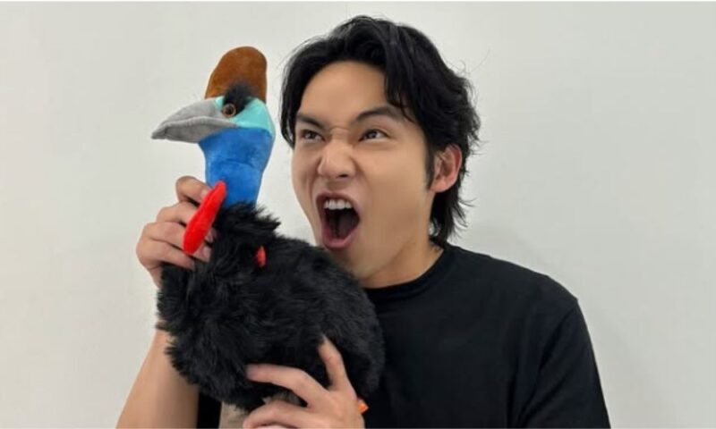 水上恒司が黒い鳥のぬいぐるみを持ち、大きく口を開けたユーモラスな表情の写真