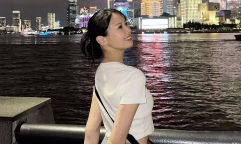 上海でレーシングミクサポーターズとして活動中の荒井つかさが夜景を背景に振り向く様子