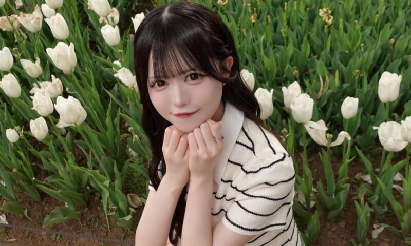 飛茉りのあが白いチューリップ畑の中で、手を顎に添えて微笑むポートレート写真