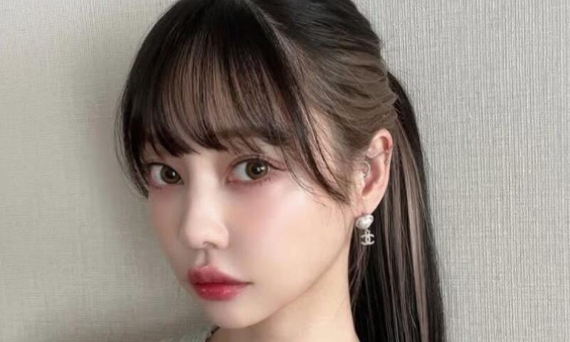 中村里砂の自撮り風アップショット。パッツン前髪のポニーテールヘアで、インナーカラーのハイライトが見える。耳元には白いパールのイヤリングを着用。