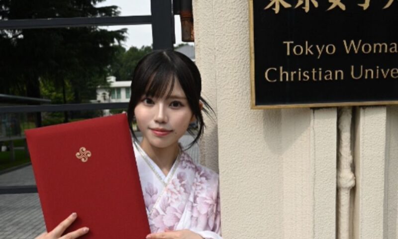 東京女子大学の正門前で学位記を手に持ち、袴姿で卒業を報告する上西萌々