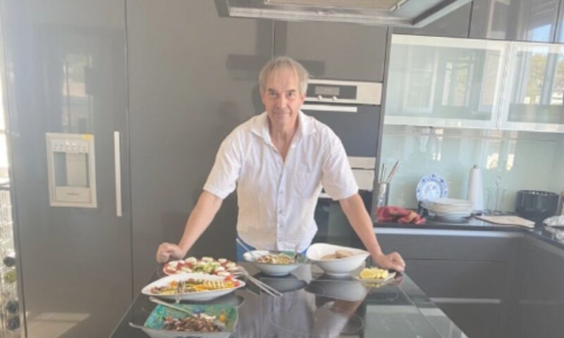 ドイツ・ハイデルベルクの豪邸のキッチンで、たくさんの手作り料理を並べて立つマーク・シュミッヒ