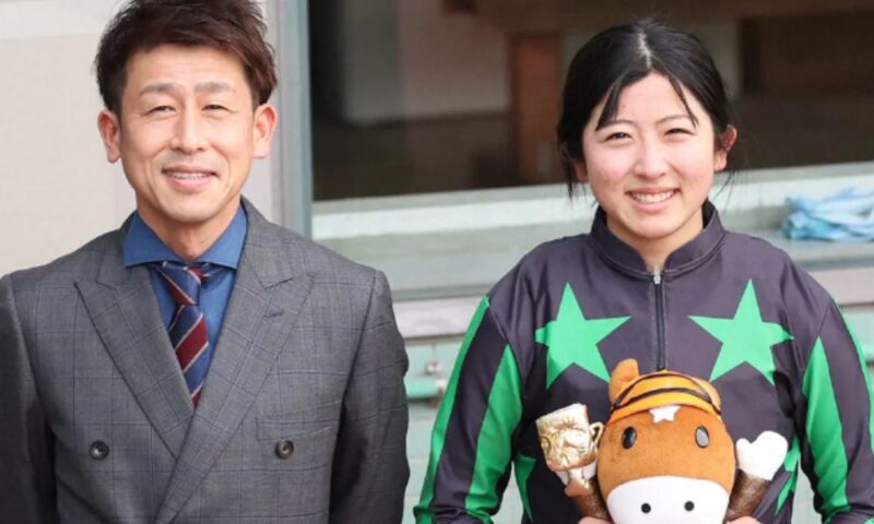 今村聖奈（騎手）と父・今村康成氏が並んで笑う。聖奈は紫の騎手服でトロフィーとぬいぐるみの馬を手に持ち、康成氏はスーツ姿