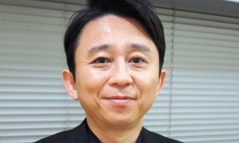 お笑い芸人・有吉弘行。黒スーツにドット柄の蝶ネクタイ姿で微笑む近影ポートレート