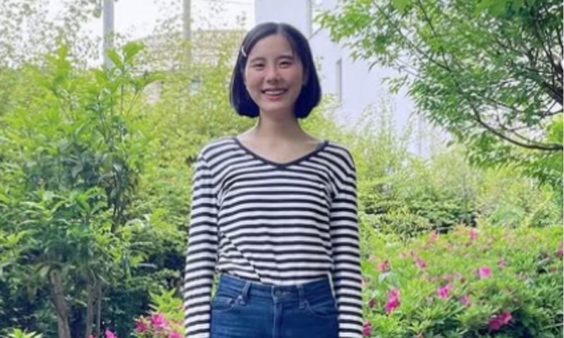 笑顔の女優・花岡すみれ、ボーダーシャツ姿で公園のピンクの花の前に立つ写真