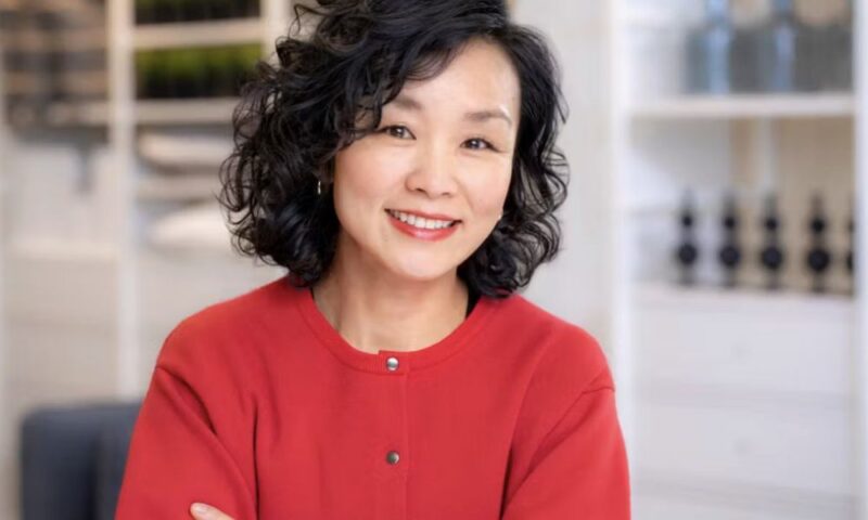 イケア・ジャパン次期社長のマティ絵莉。赤いカーディガンを着て腕を組み、店舗内を背景に微笑むポートレート